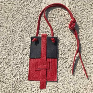 Perfekte Ledertasche für dein Handy. Die Karten kommen ins Außenfach, Geld oder Schlüssel ins Innenfach. Aus schwarzem und roten Rindsleder.